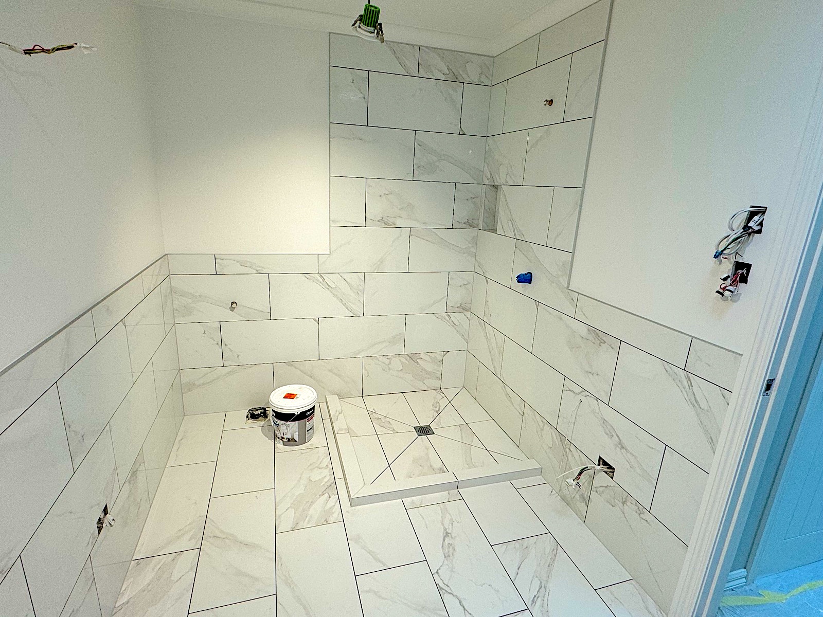 Marble wet-room bathroom with herringbone tiled wall completed by TZ Tiling