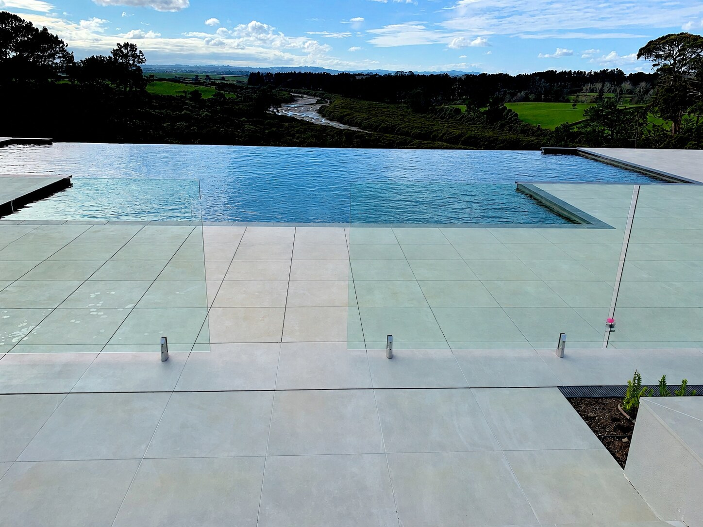 Infinity-edge pool with large-format porcelain surround tiled by TZ Tiling